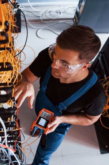 top-view-young-man-uniform-with-measuring-device-that-works-with-internet-equipment-wires-server-room